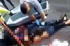 路上で死亡している男性の遺体を鍬を使い棺に納める作業員