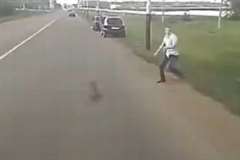 手に持っていた岩を走行中の車の目の前に放り投げる男