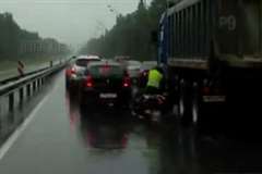 バイクの運転手がダンプカーのタイヤに踏まれる