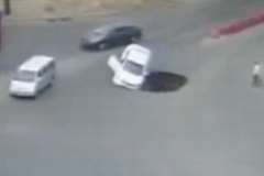 道路に出来た陥没穴に転落する車