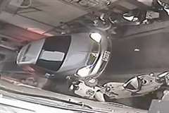 狭い路地で駐車中のスクーターを強引に押し退け通過していく車