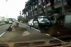 突然開かれた車のドアに2人乗りのスクーターが突っ込み転倒したところを後続車に轢かれる