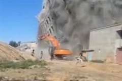 崩壊したビルのガレキに押し潰される重機