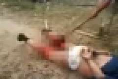 後ろ手に縛った男性の足を斧で切断する