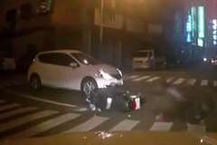 点滅信号の交差点内で車とスクーターが衝突する