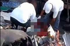 原型がわからないほど破壊された車の中から男性の死体を引きずり出す